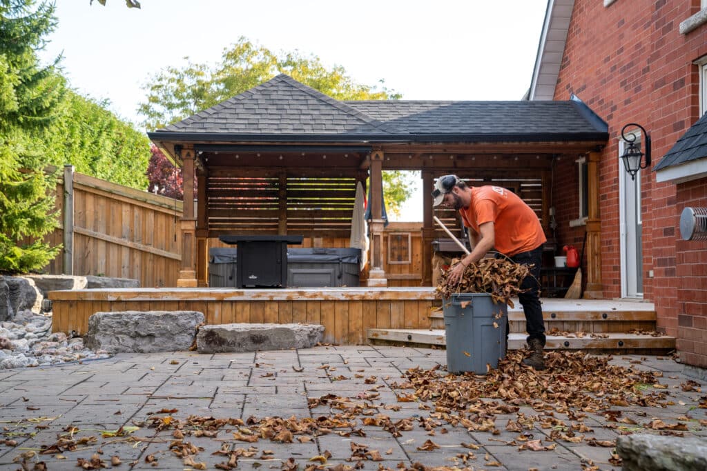 An OGS Landscape worker cleaning leafs from stone tile work on a patio.